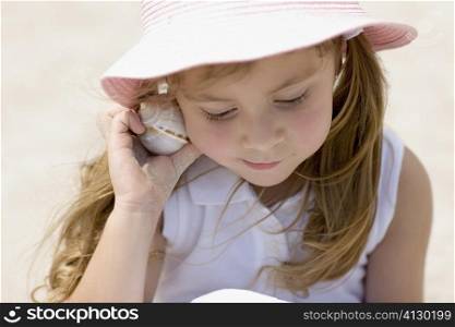 Close-up of a girl listening to a conch shell