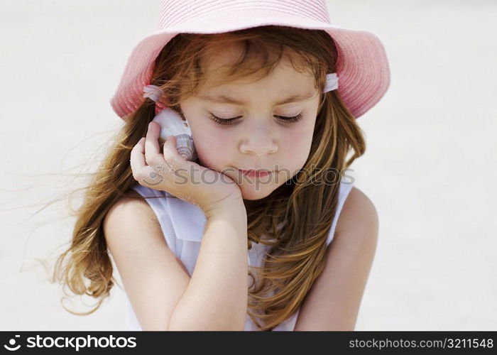 Close-up of a girl listening to a seashell