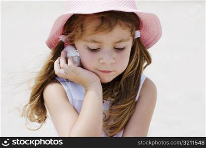 Close-up of a girl listening to a seashell