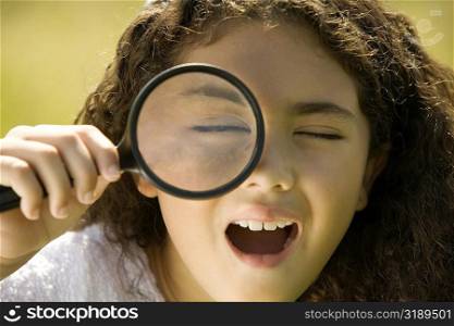 Close-up of a girl looking through a magnifying glass