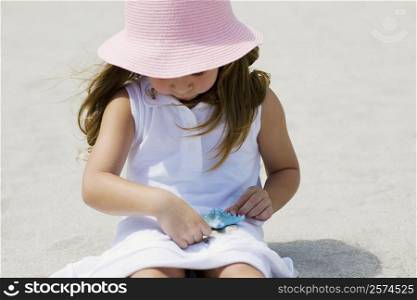Close-up of a girl playing with a starfish on the beach