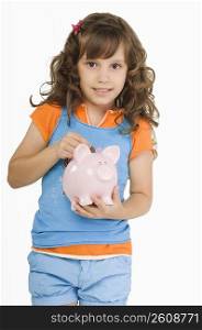 Close-up of a girl putting a coin into a piggy bank