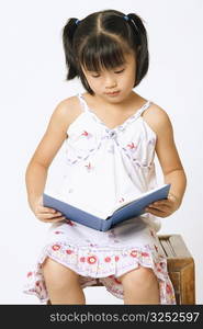 Close-up of a girl reading a book and sitting on a stool