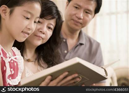 Close-up of a girl reading a book with her parents