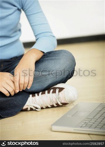 Close-up of a girl sitting beside a laptop