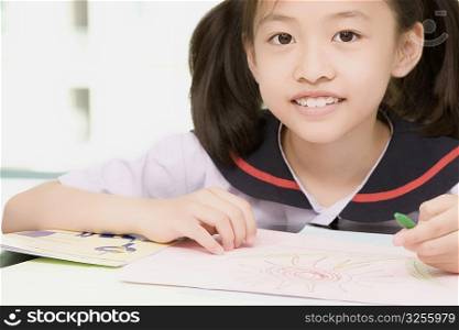 Close-up of a girl smiling and holding a colored pencil