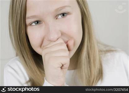 Close-up of a girl smiling with her hands covering her mouth