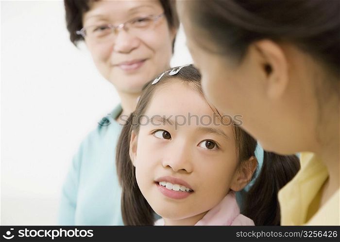 Close-up of a girl smiling with her mother and grandmother