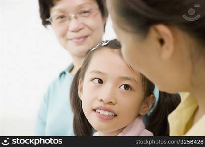 Close-up of a girl smiling with her mother and grandmother
