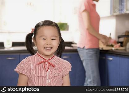 Close-up of a girl smiling with her mother standing behind her