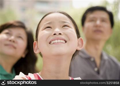 Close-up of a girl smiling with her parents in the background