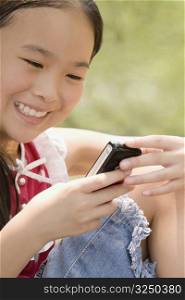 Close-up of a girl using a mobile phone and smiling
