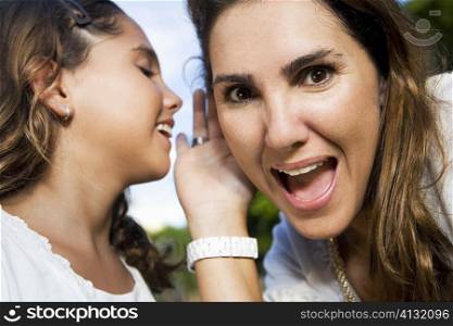 Close-up of a girl whispering into her mother&acute;s ear