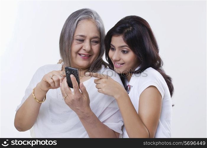 Close-up of a girl with her grandmother holding a mobile phone