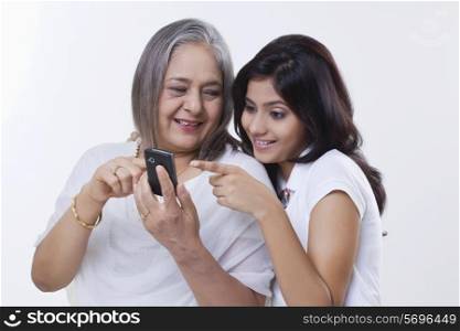 Close-up of a girl with her grandmother holding a mobile phone