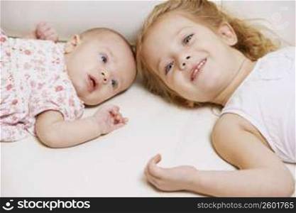 Close-up of a girl with her sister lying on the bed