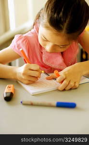 Close-up of a girl writing on a spiral notebook in the classroom