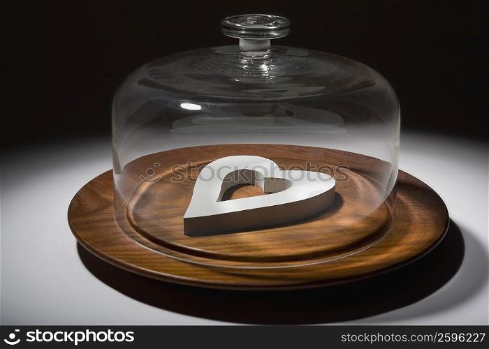 Close-up of a glass container covering a heart shaped object on a dish