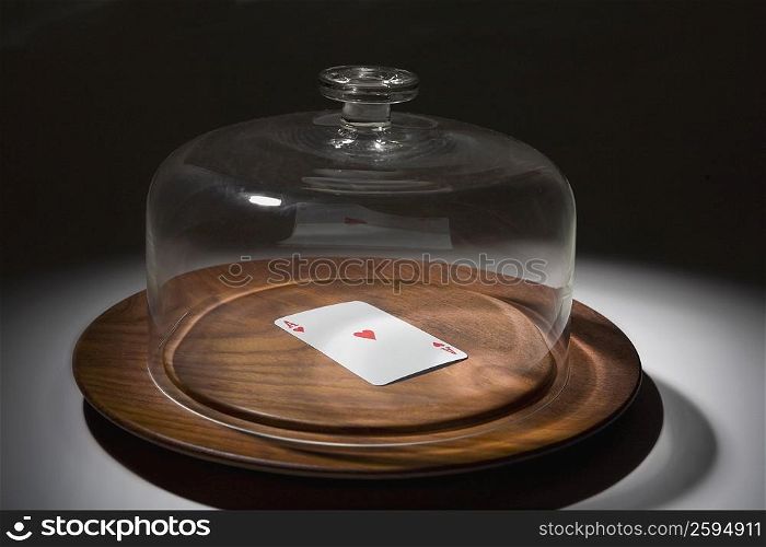 Close-up of a glass container covering a playing card on a dish