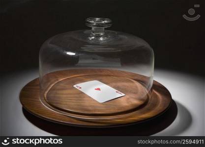Close-up of a glass container covering a playing card on a dish