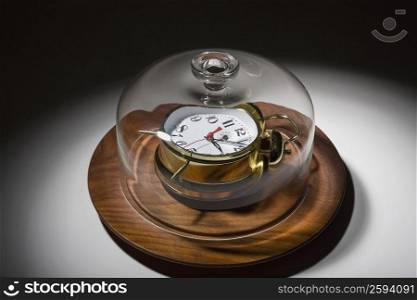 Close-up of a glass container covering an alarm clock on a dish