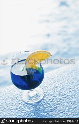 Close-up of a glass of cocktail on the ledge of swimming pool