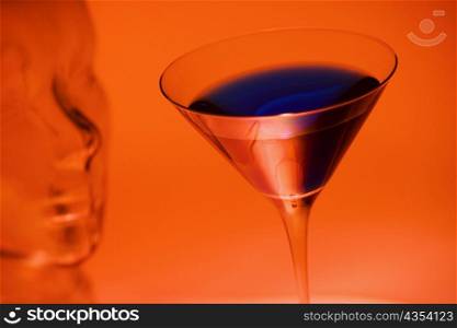 Close-up of a glass of martini near a glass mannequin