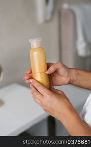 Close-up of a gold-colored moisturizer in the hands of a woman woman