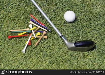 Close-up of a golf club with a golf ball and tees on the grass