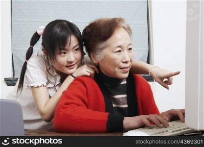 Close-up of a grandmother and her granddaughter using a computer