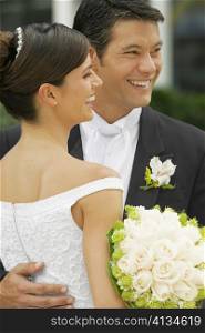 Close-up of a groom embracing his bride and smiling