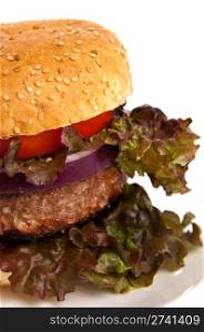 Close up of a hamburger with lettuce, tomato and purple onion isolated on white.