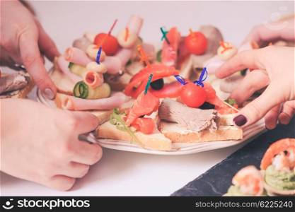 Close-up of a hands reaching out for a delicious sandwiches. The long-awaited mealtime