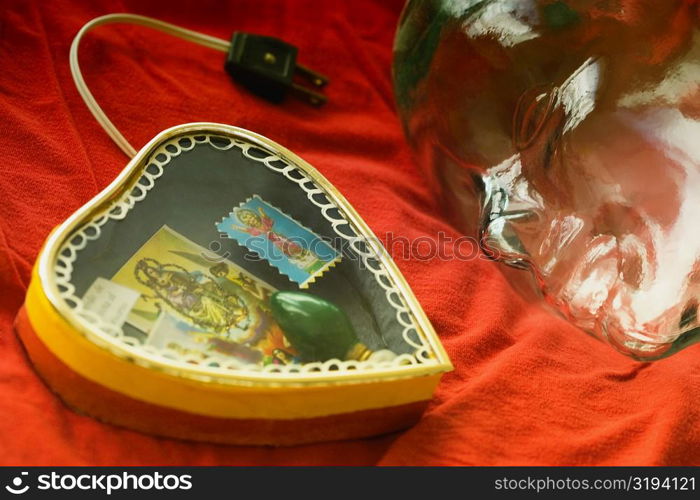 Close-up of a heart shaped lamp with a glass statue on a sheet