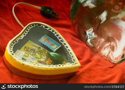 Close-up of a heart shaped lamp with a glass statue on a sheet