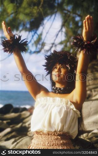 Close-up of a hula dancer standing on the beach with her arms raised, Hawaii, USA