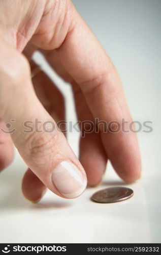 Close-up of a human finger reaching towards a coin