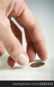 Close-up of a human finger reaching towards a coin