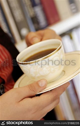 Close-up of a human hand holding a cup of black tea