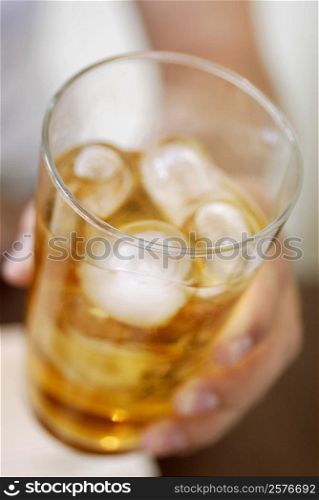 Close-up of a human hand holding a glass of ice tea