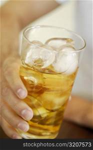 Close-up of a human hand holding a glass of whiskey