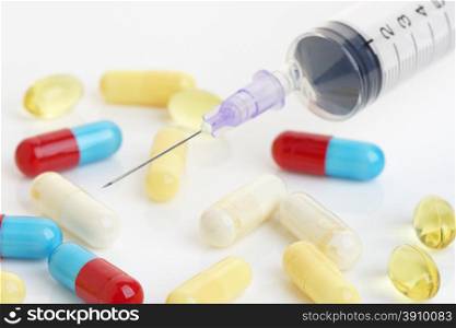 Close up of a hypodermic needle and colored capsules. Health or addiction concept.Shallow d o f.