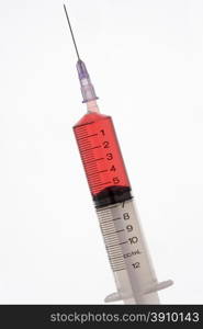 Close up of a hypodermic syringe against a white background.
