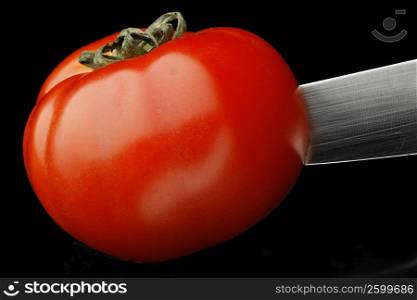 Close-up of a knife cutting a tomato
