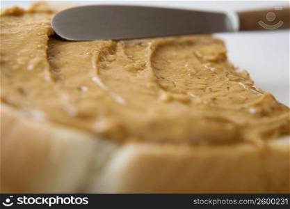 Close-up of a knife spreading peanut butter on a slice of bread