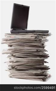 Close-up of a laptop on a stack of newspapers