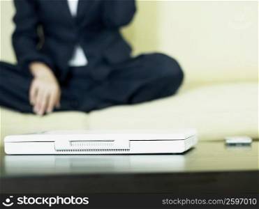 Close-up of a laptop with a business executive sitting beside it