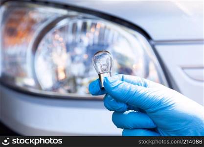 Close up of a light bulb with car headlight in the background