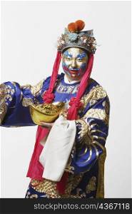 Close-up of a male Chinese opera performer holding a bowl full of gold coins