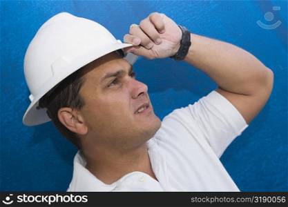 Close-up of a male construction worker adjusting his hardhat